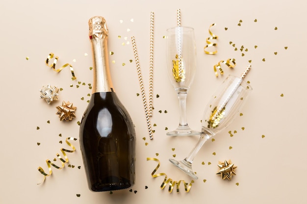 bottle of champagne with glasses and colorful confetti on colored background top view flay lay