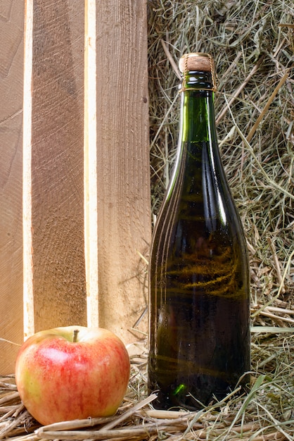 Photo bottle of cider with a apple and straw