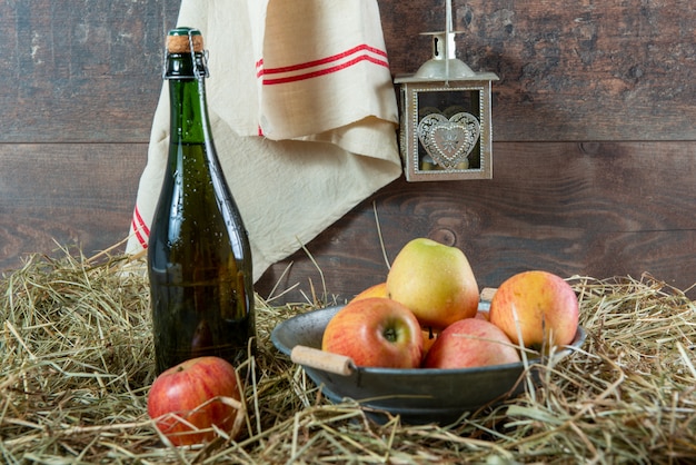 Bottle of cider with apples on the straw