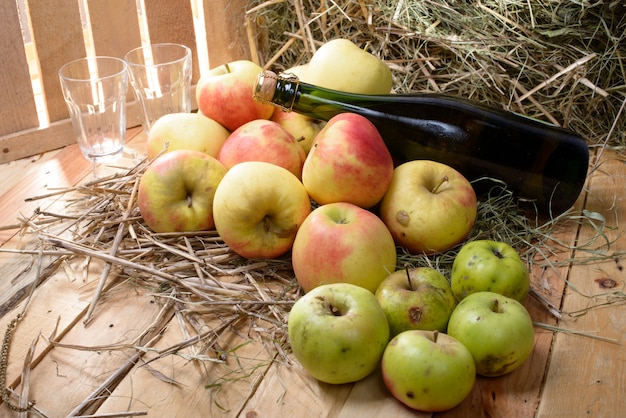 Bottle of cider with some apples and straw