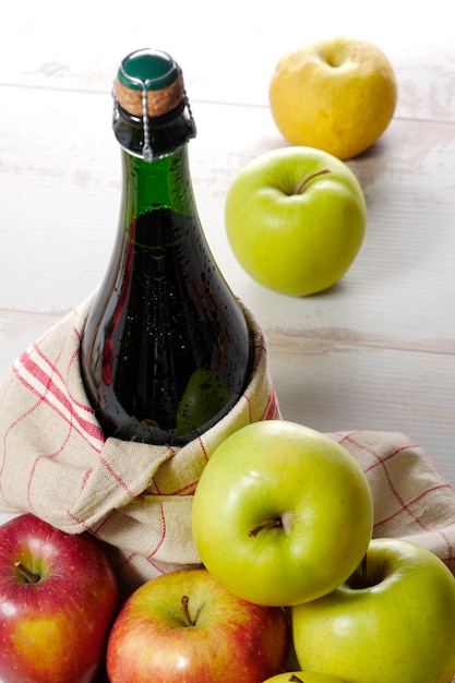 Photo bottle of cider with yellow and red apples