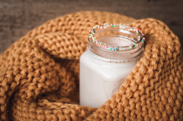 A bottle of cocoa with a yellow knitted scarf