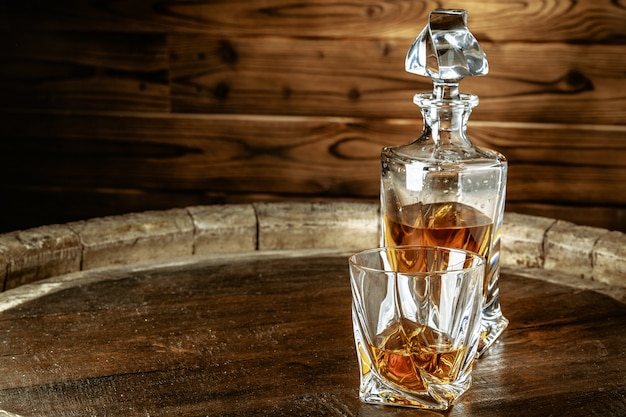 A bottle of cognac and glass on a brown wooden table. Brandy