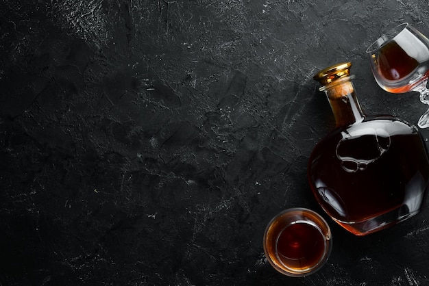 Photo a bottle of cognac and glasses on a black background brandy top view free space for your text