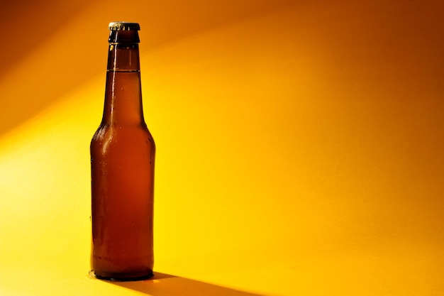 Photo bottle of cold beer closed on yellow background with shadows