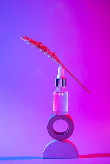 Bottle of cosmetic serum in neon light