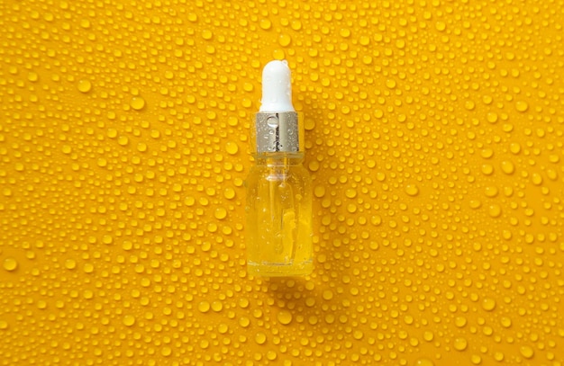 Photo bottle of cosmetics and drops of liquid moisturizing hyaluronic acid selective focus