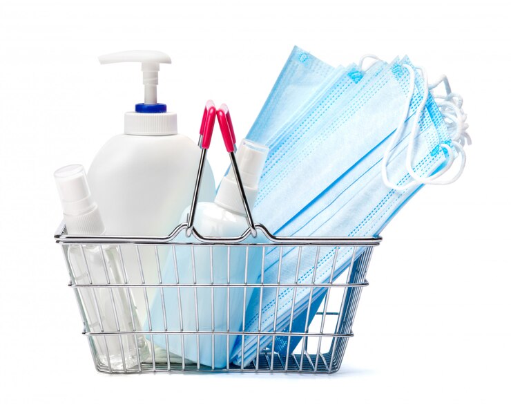 Photo bottle of cream, lotion, sanitizer or liquid soap and protective mask in shopping cart basket on white table