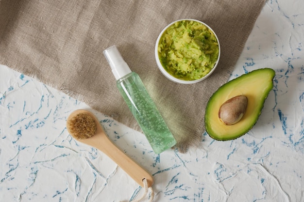 Bottle of cream with avocado slices on a green background Natural cosmetics concept