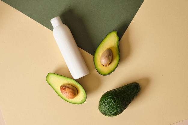 A bottle of cream with avocado slices on a green background Natural cosmetics concept