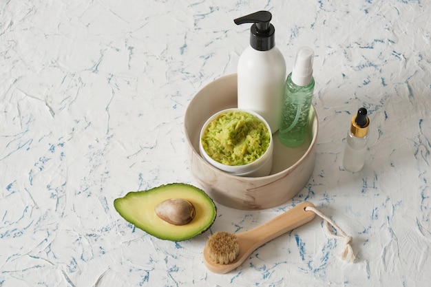 A bottle of cream with avocado slices on a light background Natural cosmetics concept