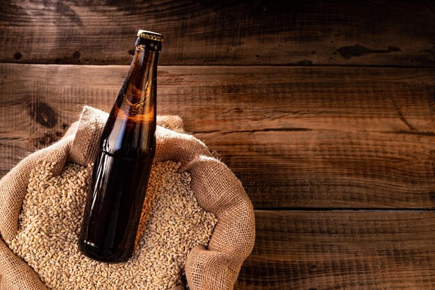 A bottle of dark beer in a bag of wheat A beam of light falls on a bottle of beer