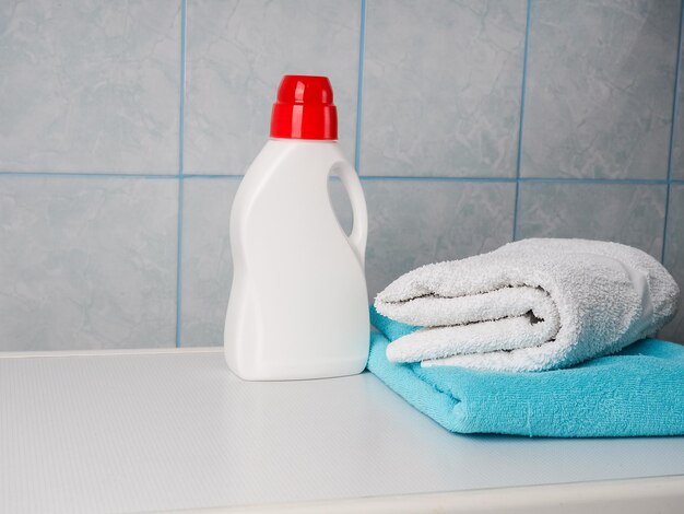 Photo bottle of detergent and clean towels on washing machine indoors space for text laundry day