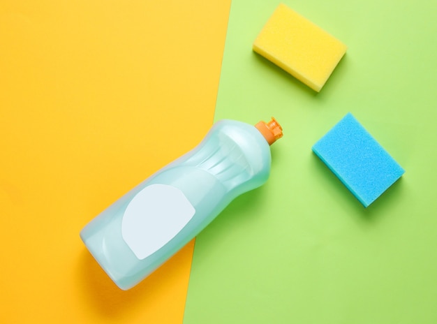 A bottle of detergent gel for dishes, sponges on a colored paper