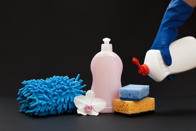 Bottle of detergent a rag and sponges on the black background