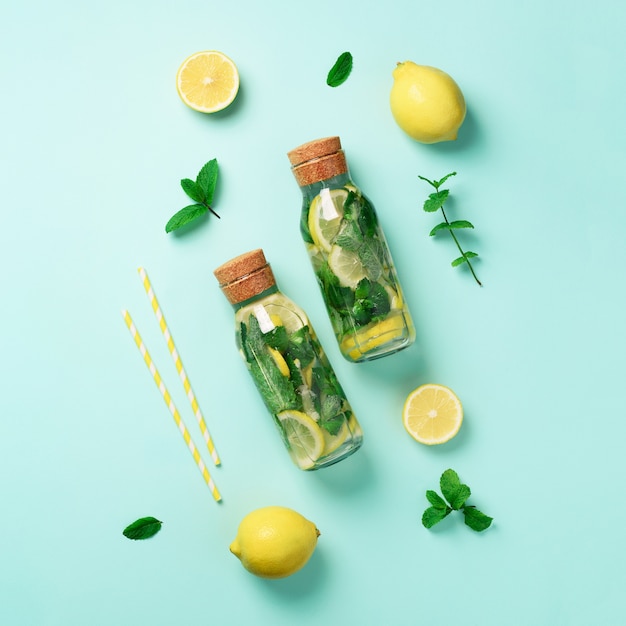 Bottle of detox water with mint, lemon on blue background. 