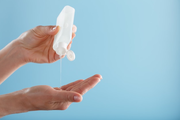 A bottle of Disinfectant gel in your hands on a blue background. Antiseptic treatment of hands from bacteria Sanitizer.