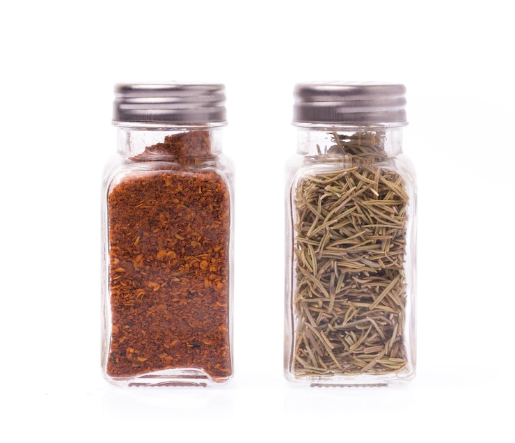 Photo bottle of dried rosemary and cayenne pepper isolated on white background