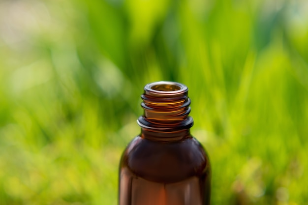 Bottle for essential oil on a green spring background. Essential oil bottle in a spring garden. Spring essential oil.