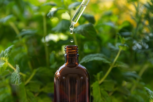 A bottle of essential oil is being poured into a glass bottle.