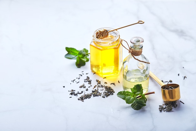 Foto bottiglia di olio essenziale di menta e foglie verdi e vasetto di miele ingredienti biologici naturali per co...