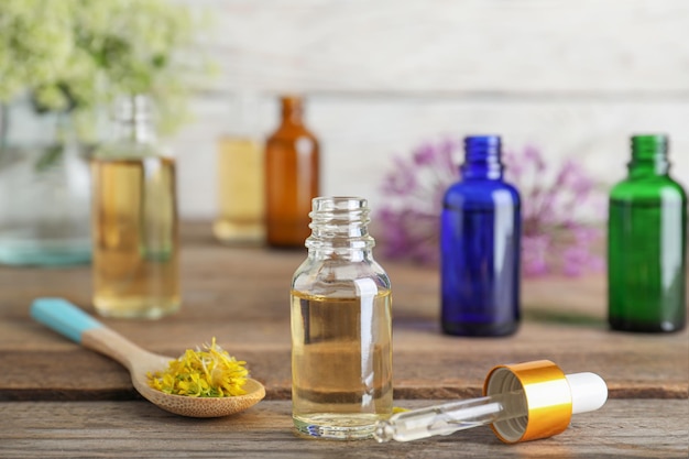 Photo bottle of essential oil pipette and spoon with flowers on wooden table space for text