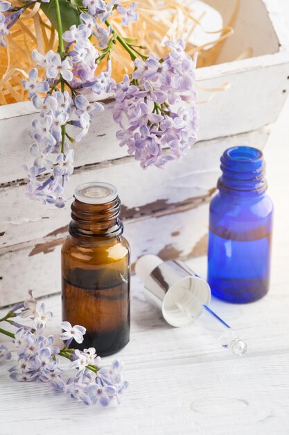 Bottle of essential oil with fresh lilac flower