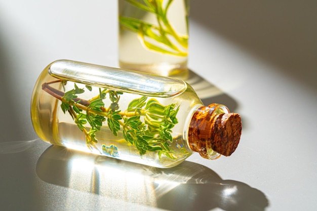 Photo bottle of essential oil with herbs on gray background