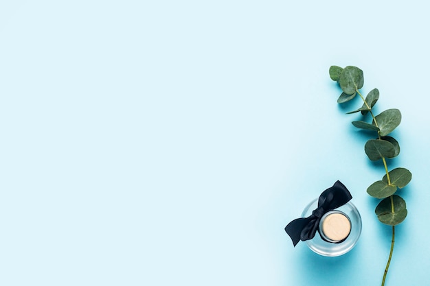 Photo bottle of eucalyptus essential oil, green eucalyptus branch against blue background. top view, flat lay.