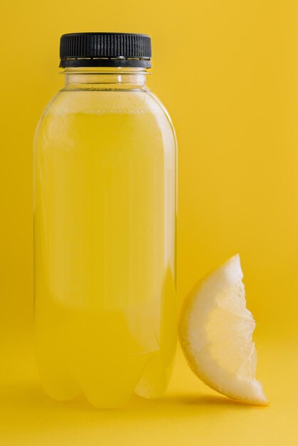 Foto bottiglia di succo di limone fresco su sfondo giallo