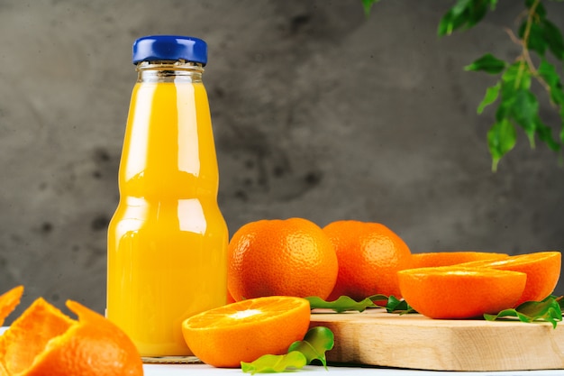 Bottle of fresh orange juice on wooden table against white brick wall
