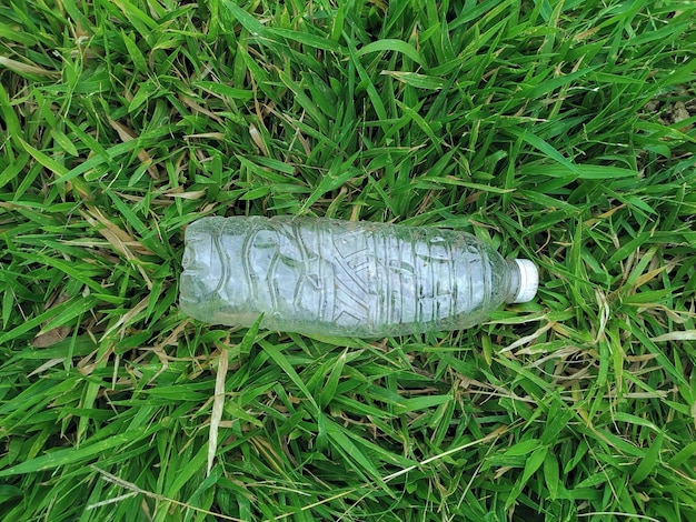 Photo bottle of fresh water on green grass top view