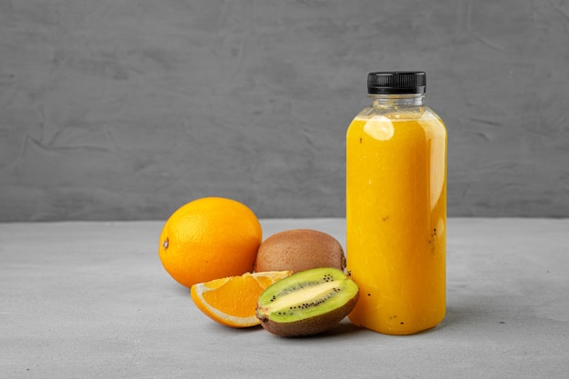 Bottle of freshly squeezed orange juice on gray background