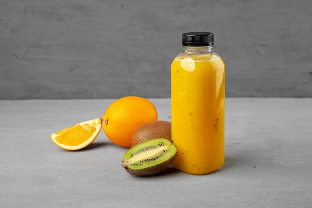 Bottle of freshly squeezed orange juice on gray