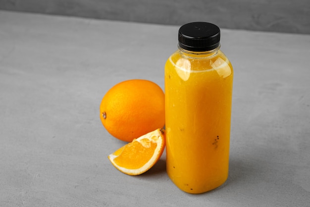 Bottle of freshly squeezed orange juice on gray