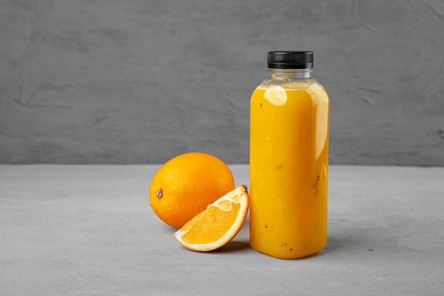 Bottle of freshly squeezed orange juice on gray