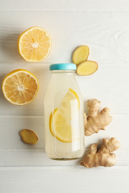 Bottle of ginger lemon water on white wooden background