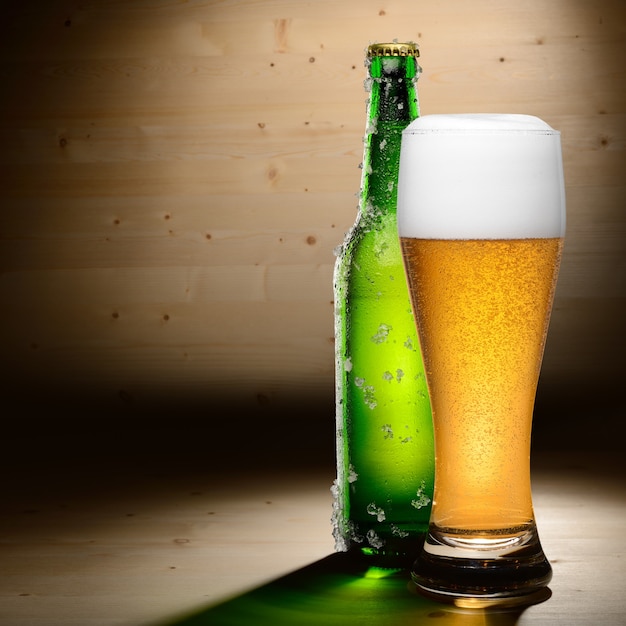 Bottle and glass of beer on wood background with copyspace