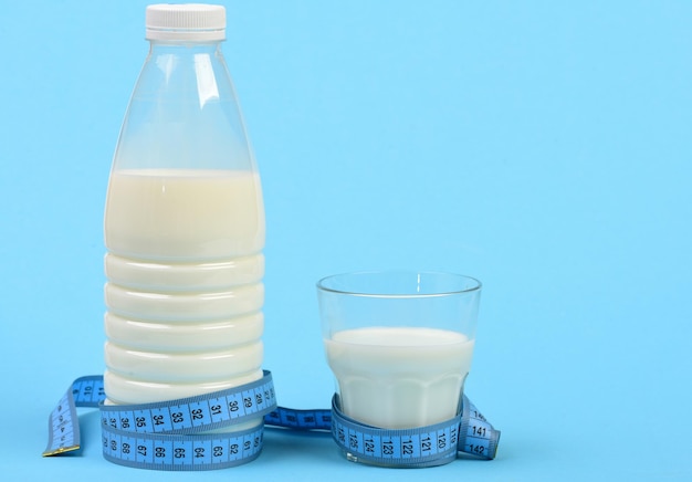 Bottle and glass of milk with blue measuring tape