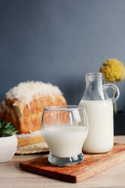 A bottle and a glass of milk with loaf bread on wooden table