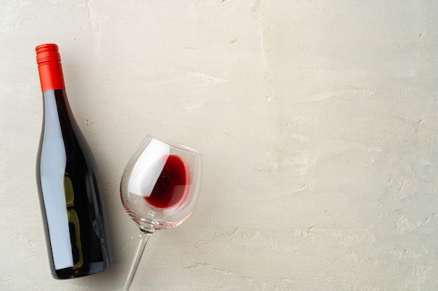 Photo bottle and glass of red wine flat lay on gray background top view