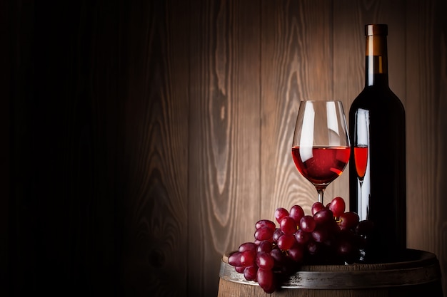 Bottiglia e bicchiere di vino rosso con uva