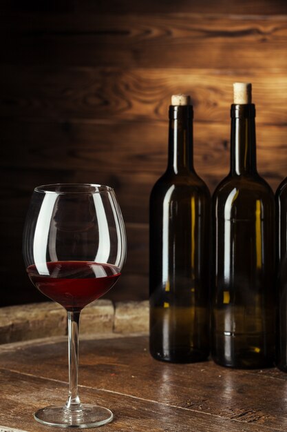 Bottle and glass of red wine on wooden barrel shot with dark wooden 