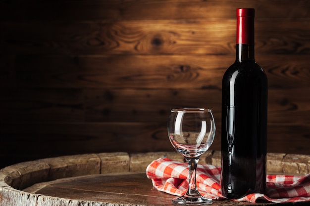 Bottle and glass of red wine on wooden barrel