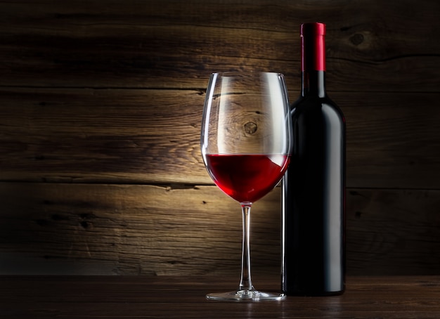 Bottle and glass of wine on a wooden background