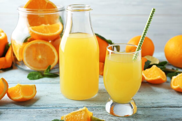 Bottle and glass with orange juice on wooden table