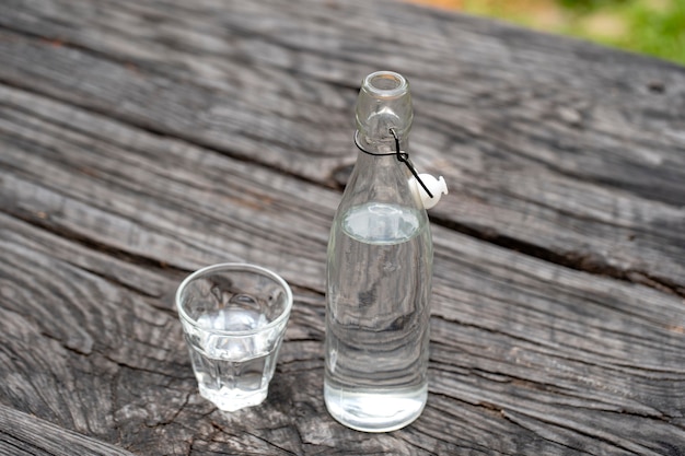 Bottle and glass with water on the wooden table, close up