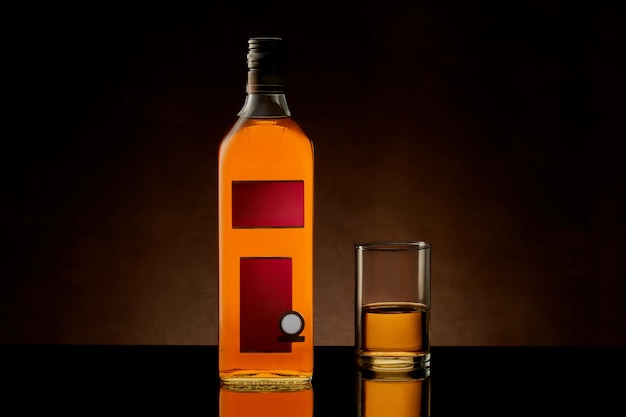 Photo bottle and glass with whiskey cognac brandy on a dark brown background