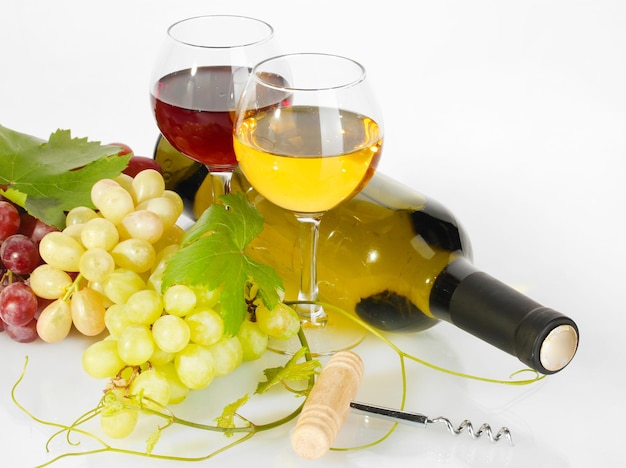 Bottle and glasses of wine and ripe grapes isolated on white