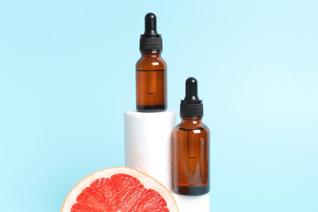 Bottle of grapefruit essential oil on light blue background